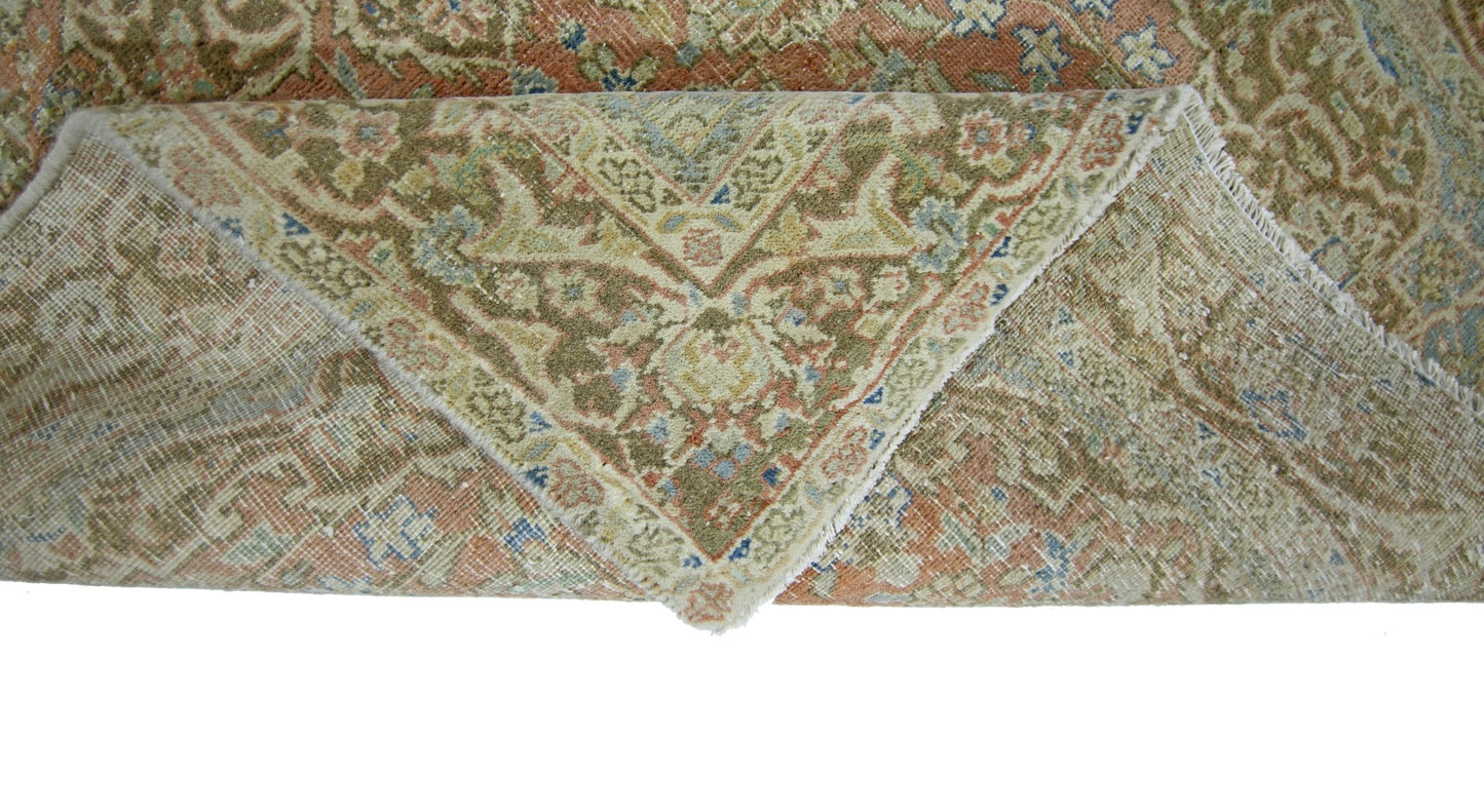 A vintage handmade Persian rug with a folded corner revealing its wool pile and cotton foundation.