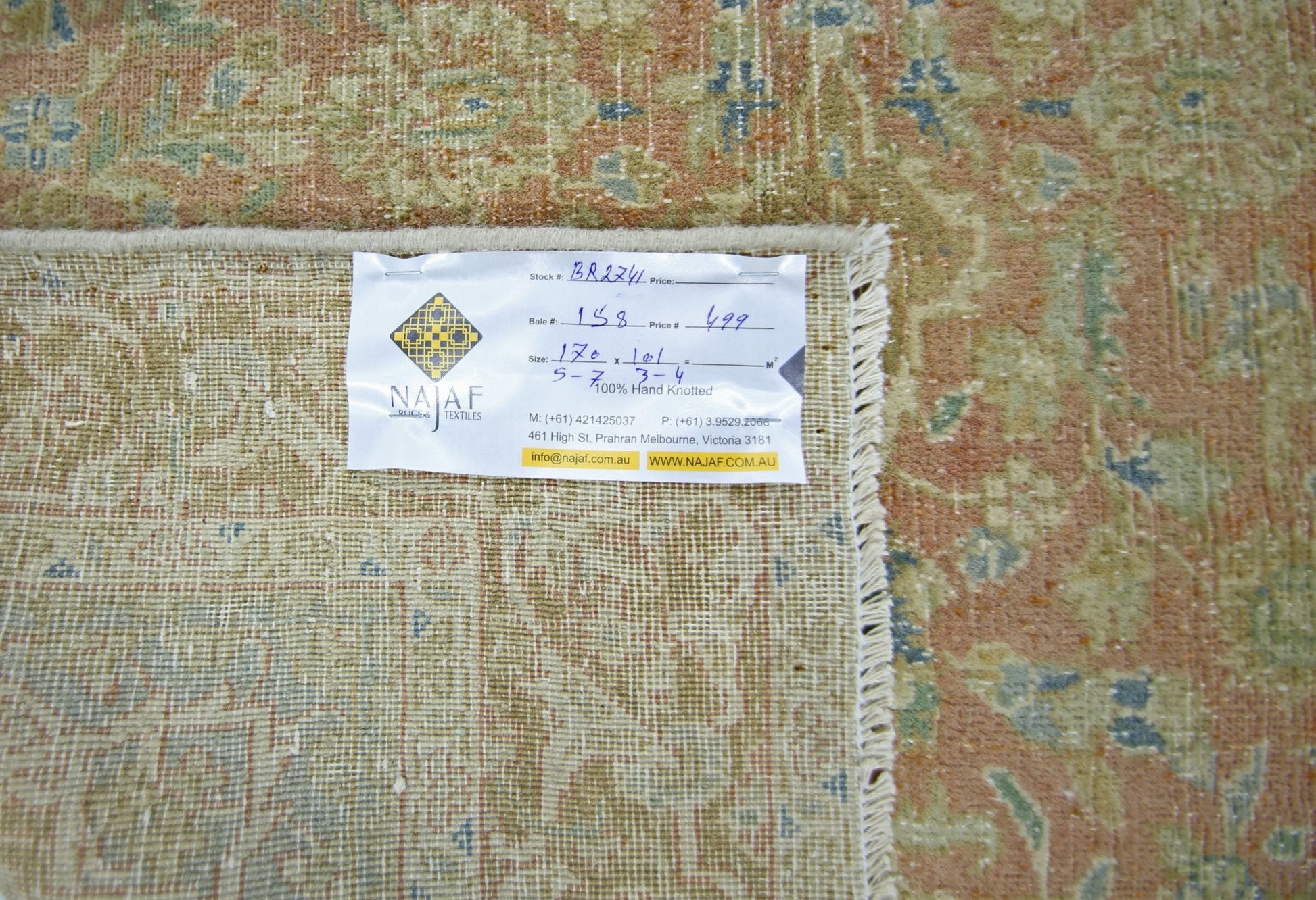 A vintage Persian rug with a faded floral pattern in shades of orange, green, and blue.