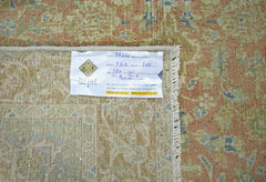 A vintage Persian rug with a faded floral pattern in shades of orange, green, and blue.