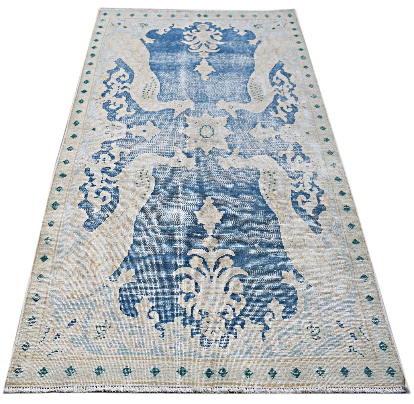 A vintage Persian Kerman rug featuring a blue central medallion and intricate floral motifs.