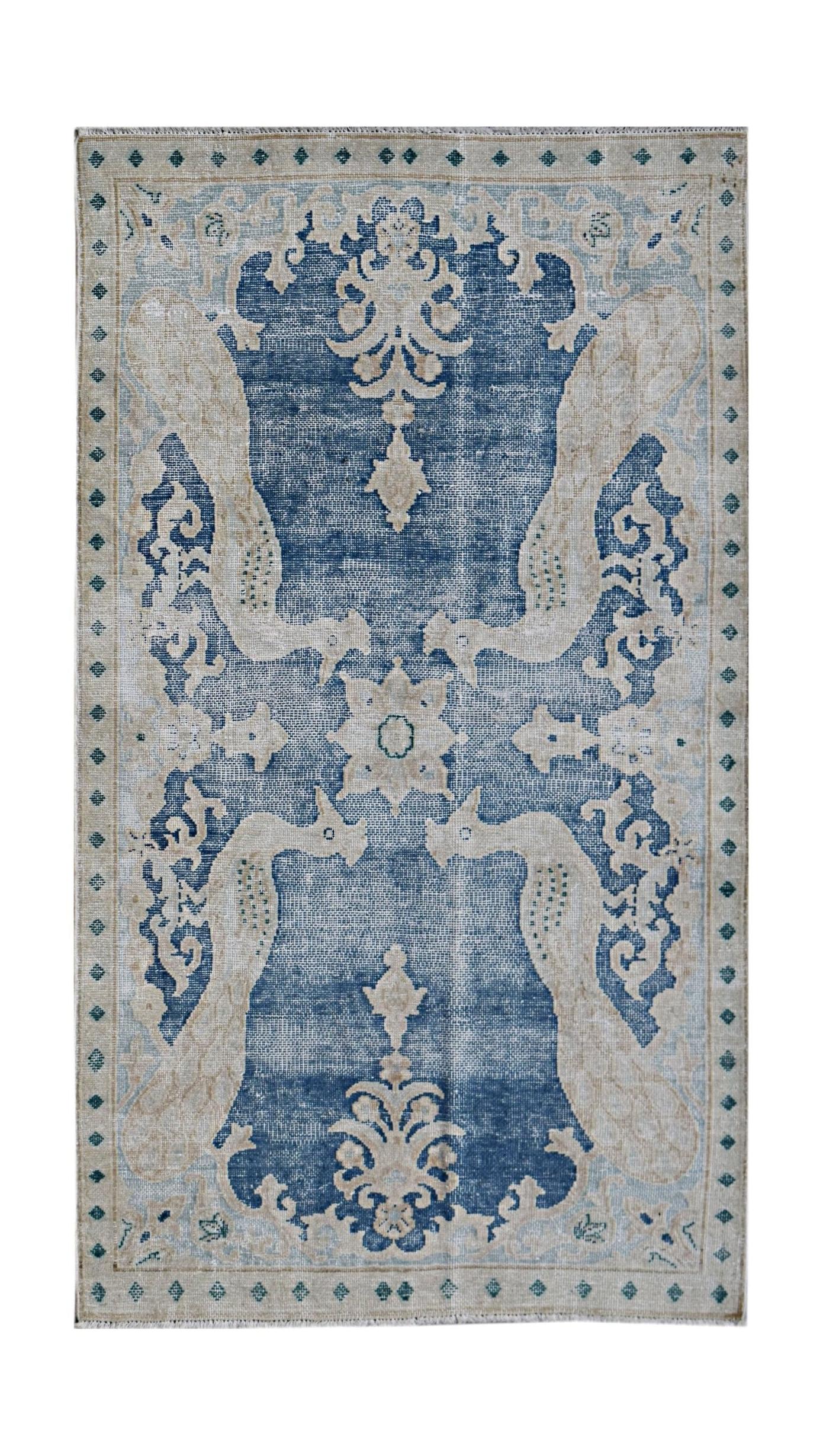 A vintage Persian Kerman rug featuring a blue field with intricate cream floral and bird motifs.