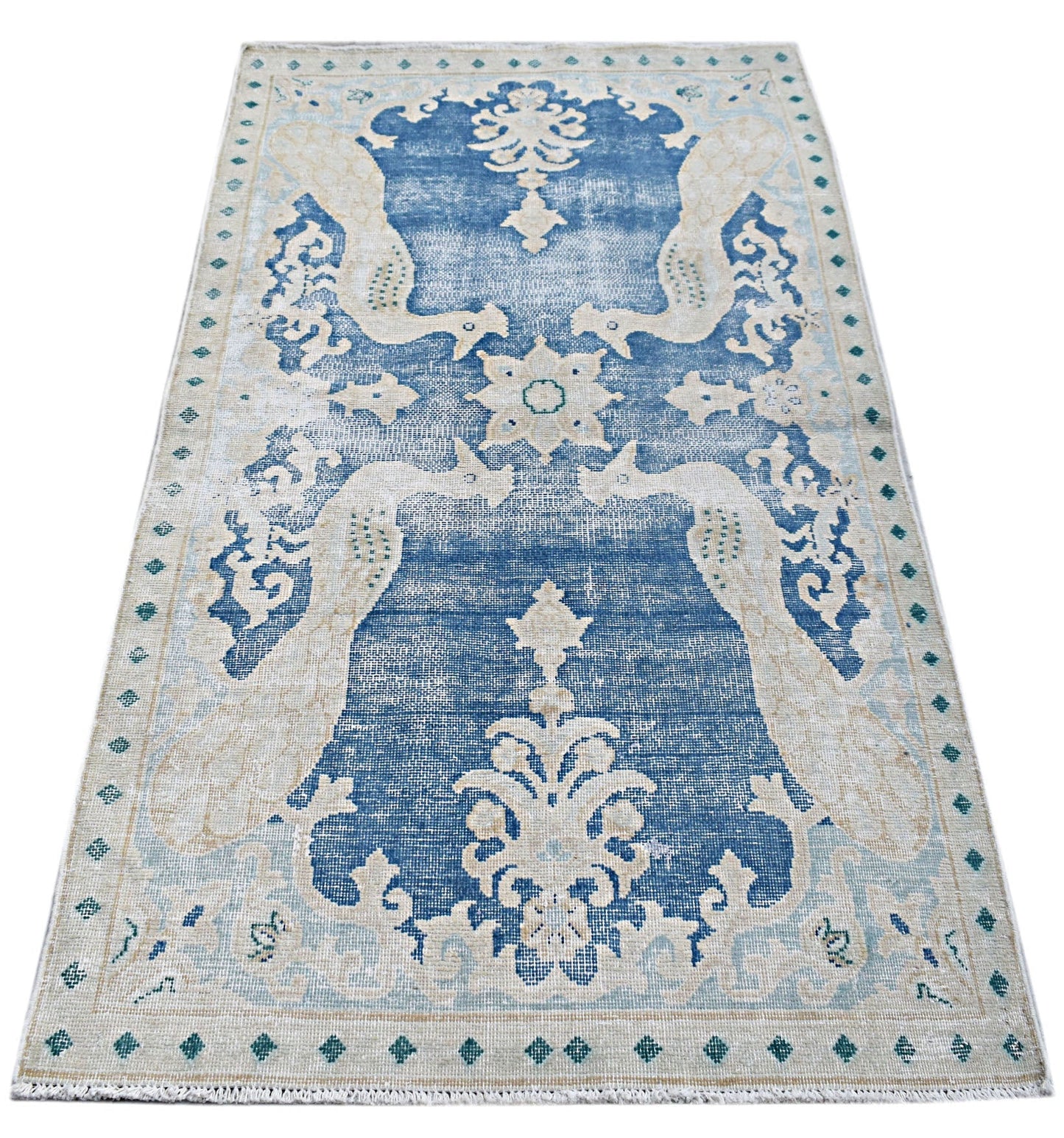 A vintage Persian Kerman rug featuring a blue field with intricate cream floral and bird motifs.