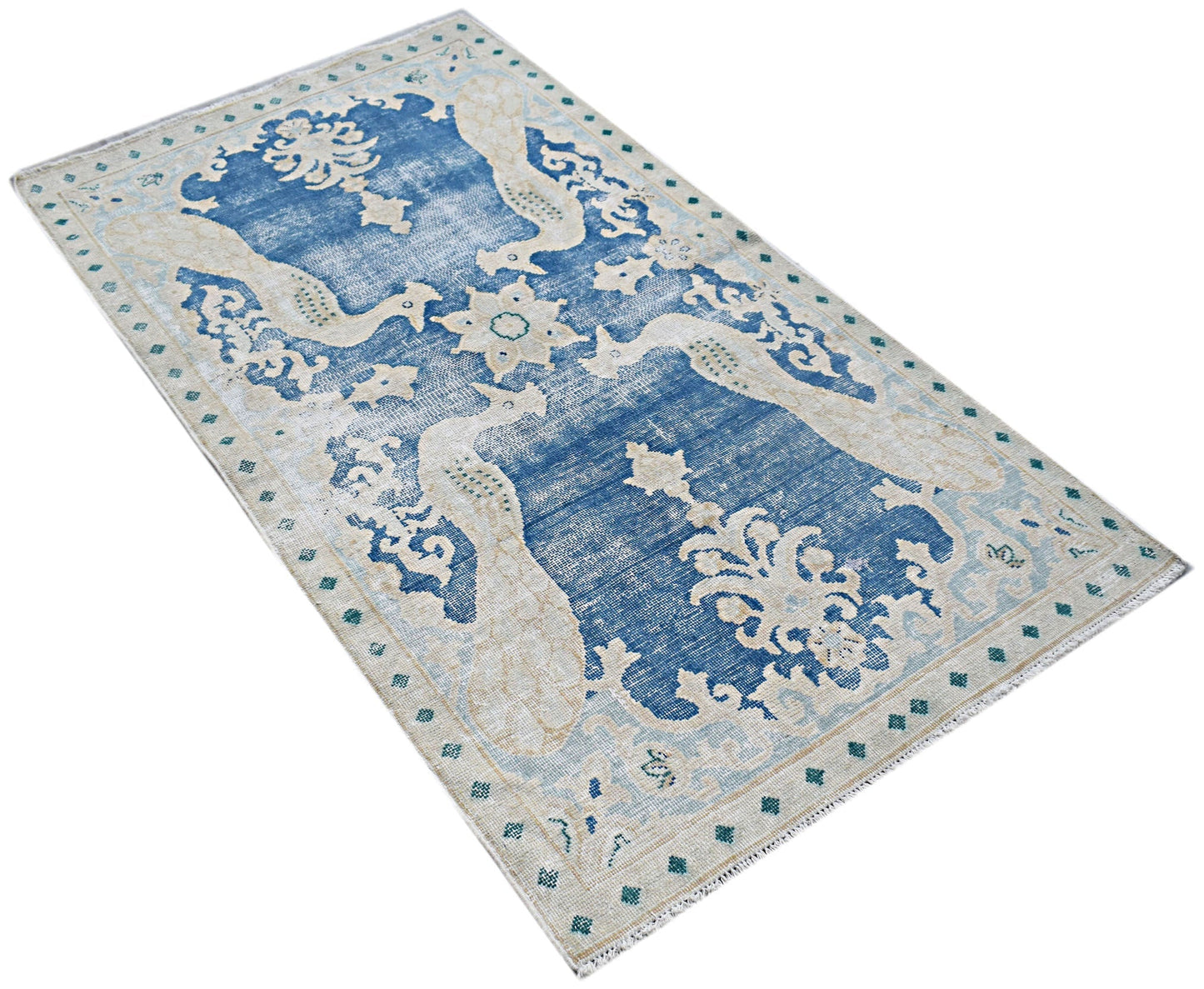 A vintage Persian Kerman rug featuring a blue field with intricate cream floral and bird motifs.