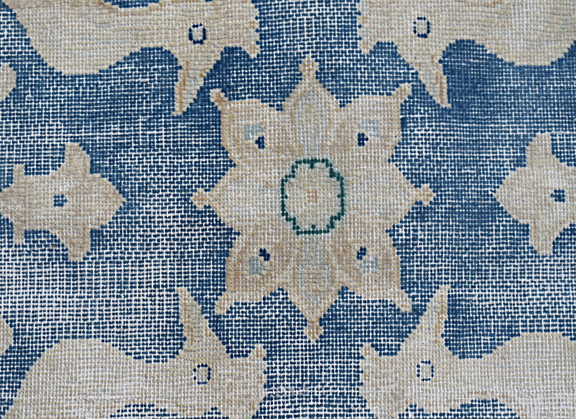 A close-up of a vintage Persian Kerman rug featuring a central floral medallion on a blue field.
