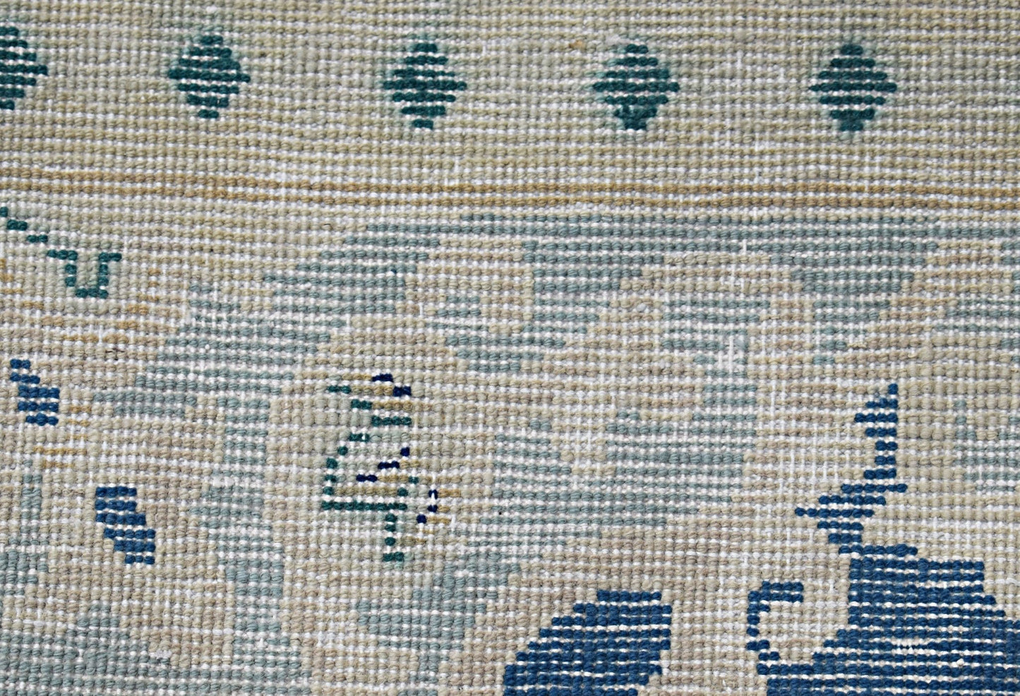 A close-up of a vintage Persian Kerman rug featuring blue geometric patterns on a textured base.