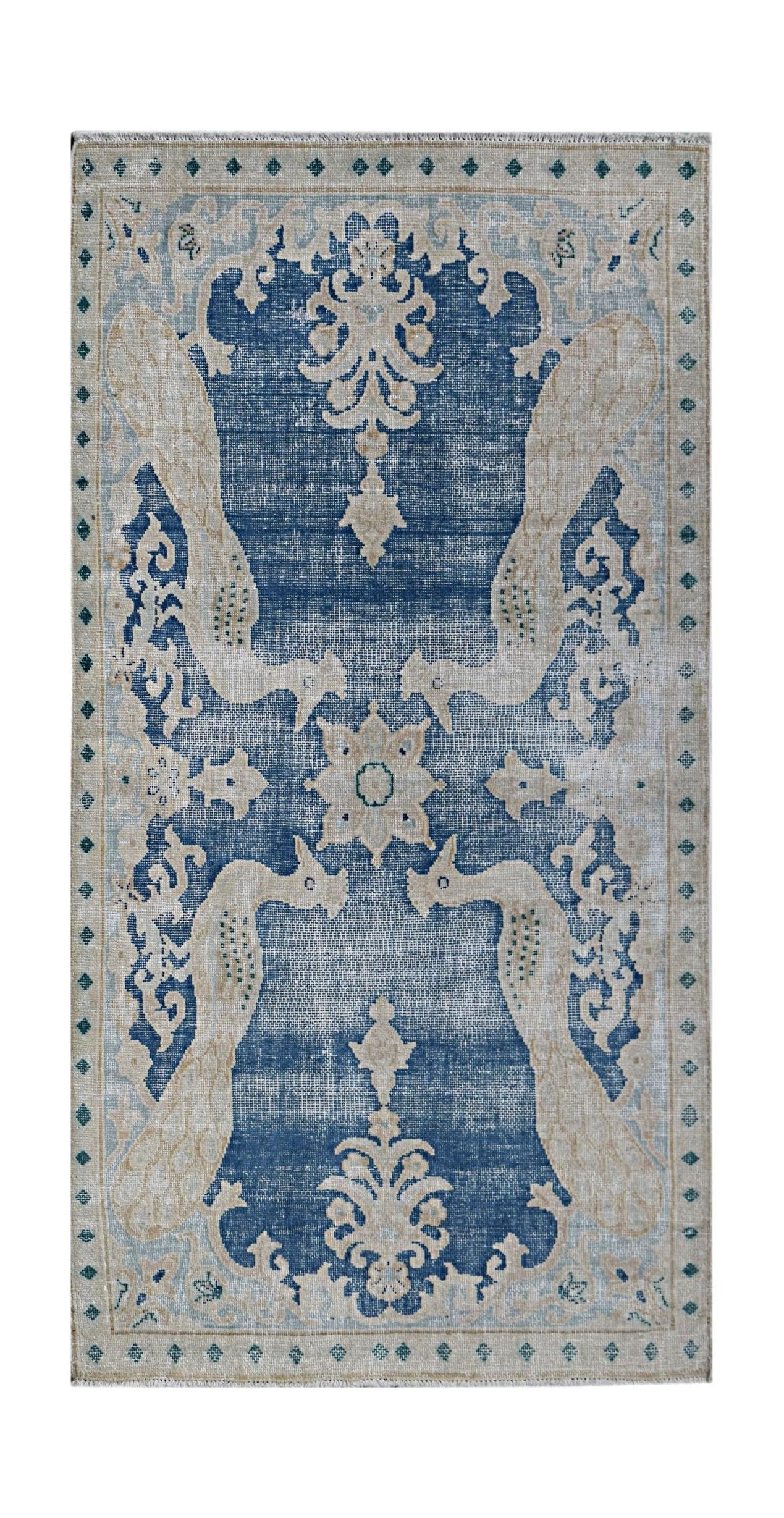 A vintage Persian Kerman rug featuring a blue field with symmetrical bird and floral motifs.
