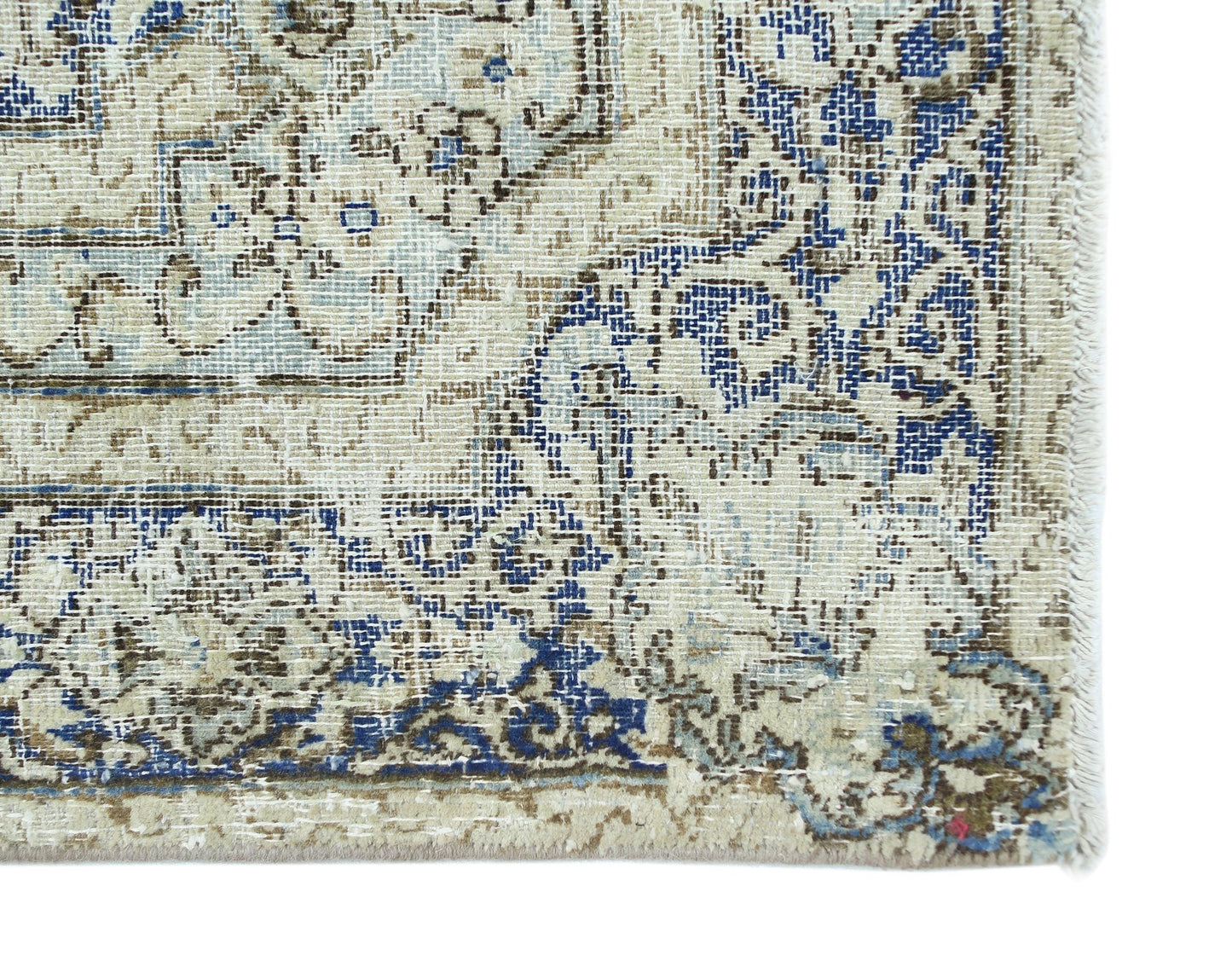A vintage Persian Kerman rug featuring intricate blue and brown floral patterns on a cream field.