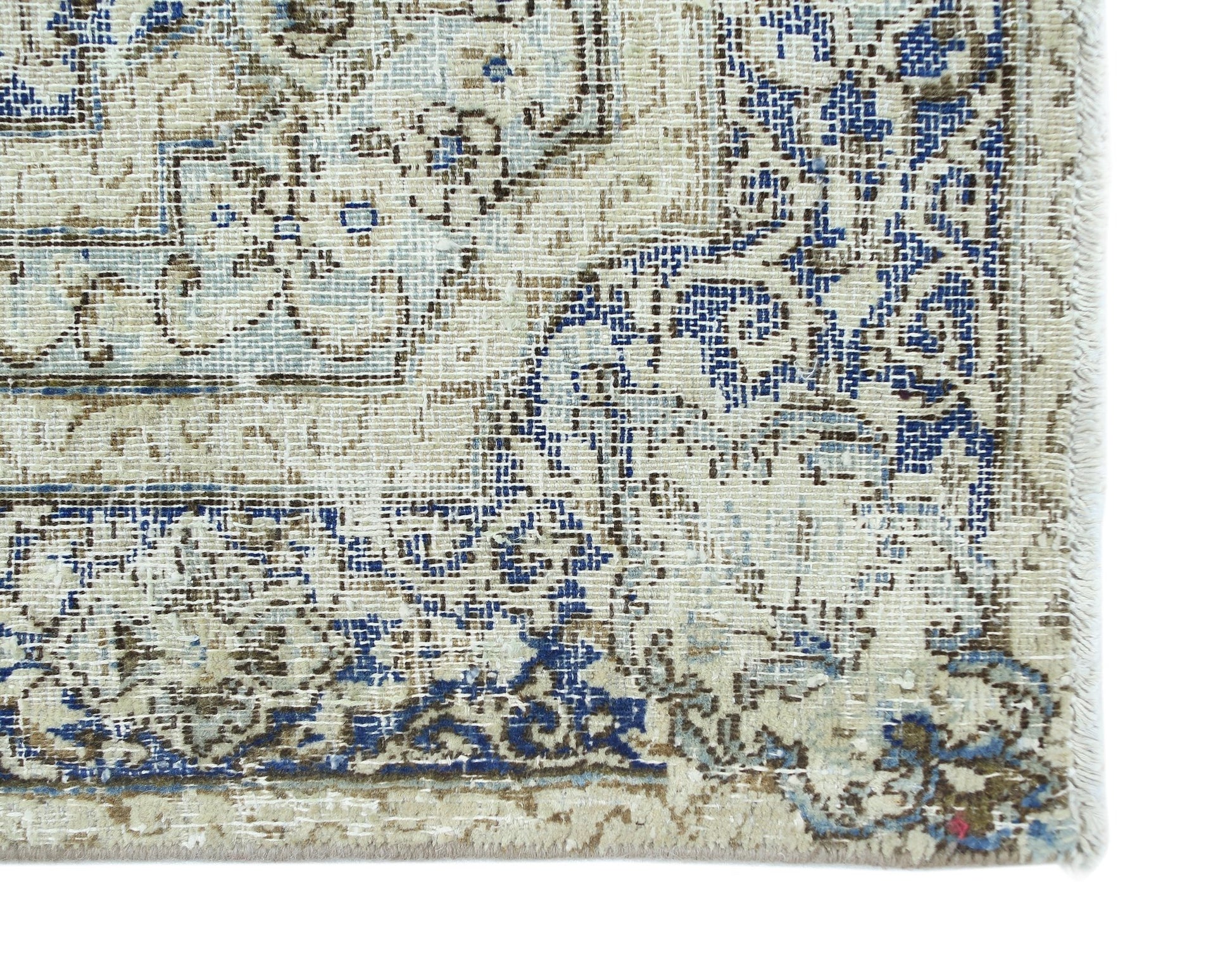 A vintage Persian Kerman rug featuring intricate blue and brown floral patterns on a cream field.