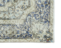 A vintage Persian Kerman rug featuring intricate blue and brown floral patterns on a cream field.