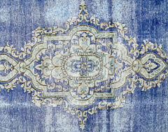 A vintage Persian Kerman rug featuring an intricate central medallion in shades of blue and cream.