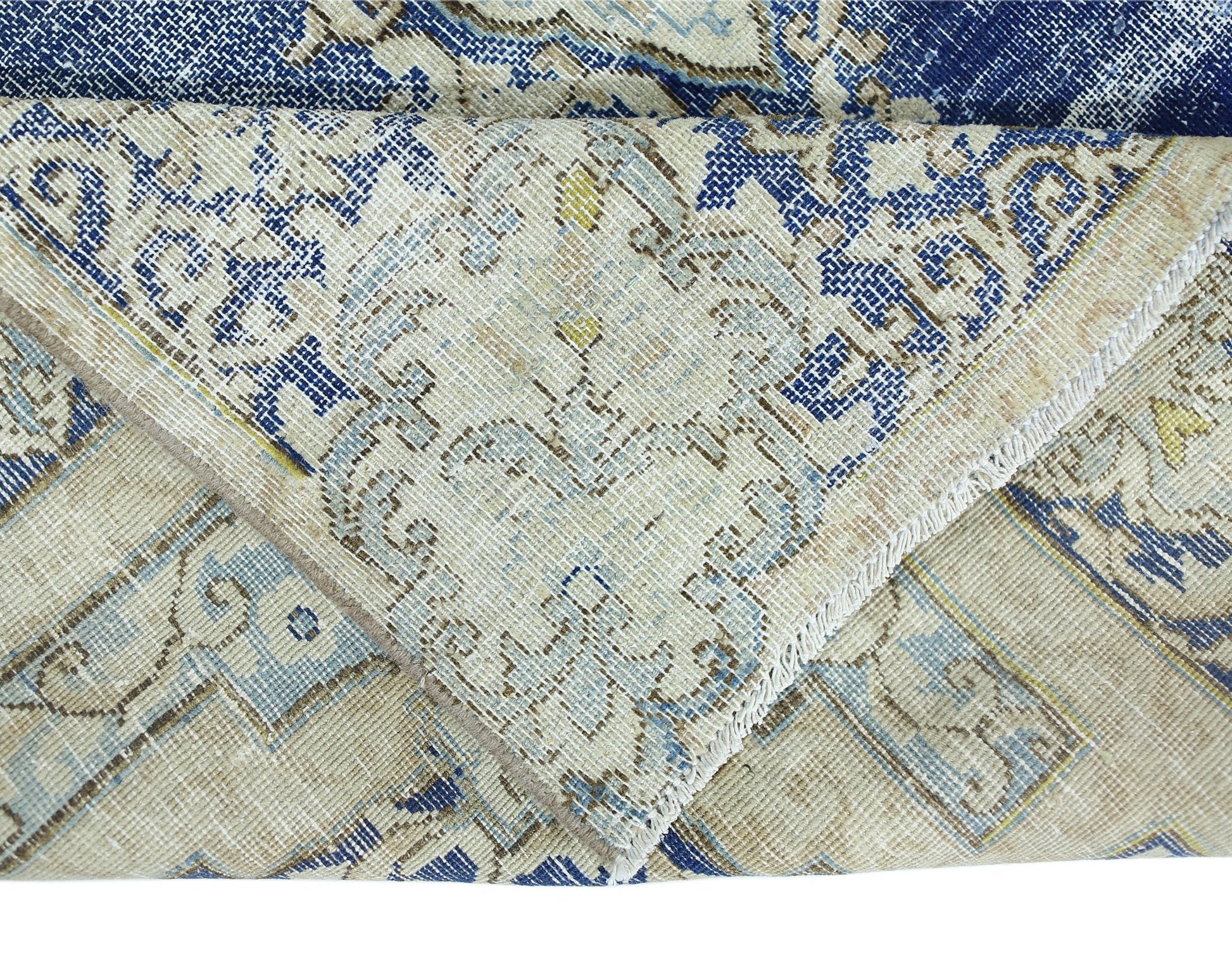 A folded vintage Persian Kerman rug featuring a blue and beige floral medallion pattern.