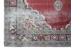 A vintage Persian Kerman rug featuring a deep red field with intricate floral and medallion motifs.