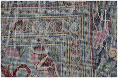 A close-up of a vintage Persian Kerman rug featuring intricate floral patterns and a blue border.