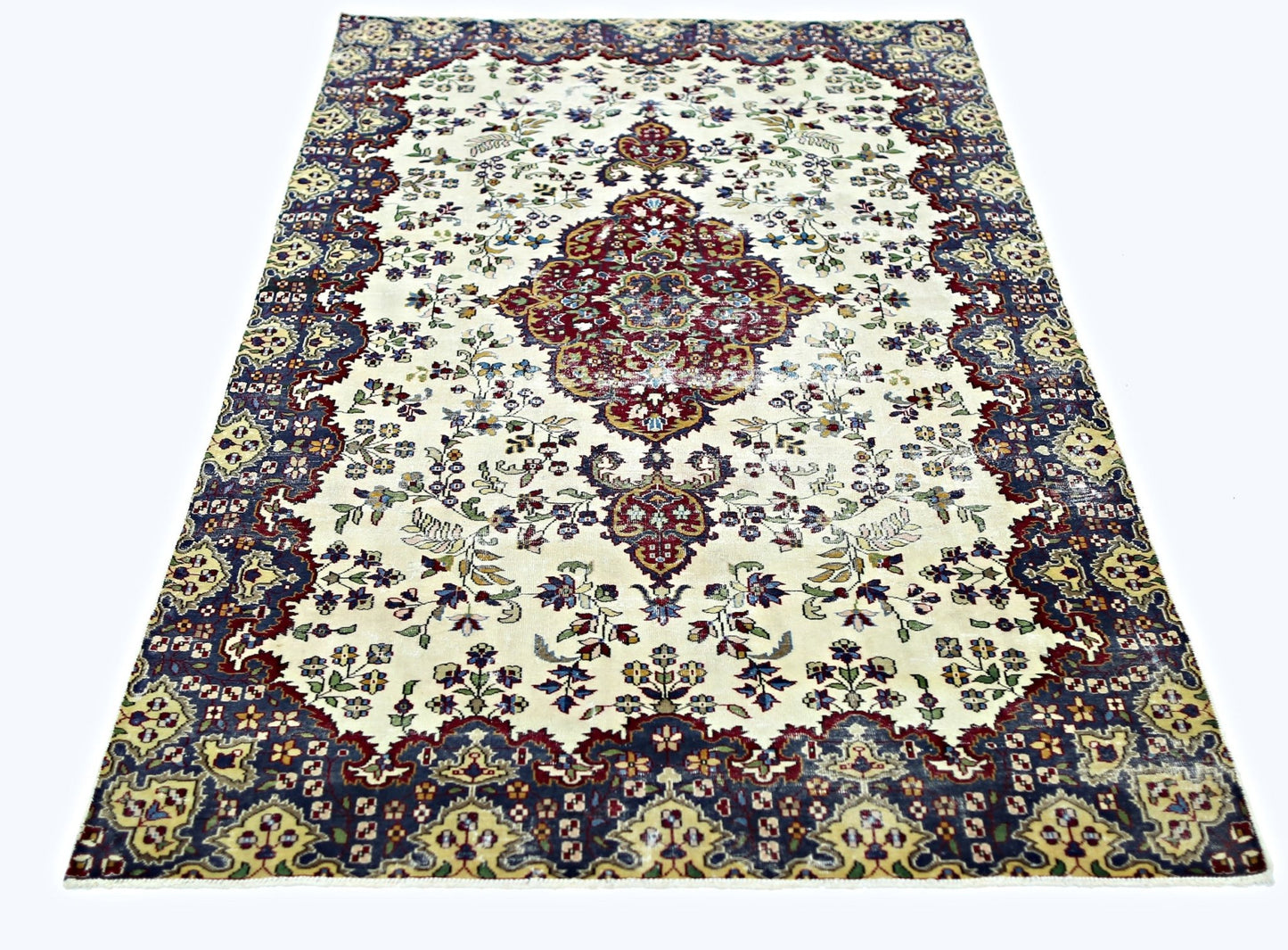 A vintage Persian Kerman rug featuring a central medallion and intricate floral patterns.
