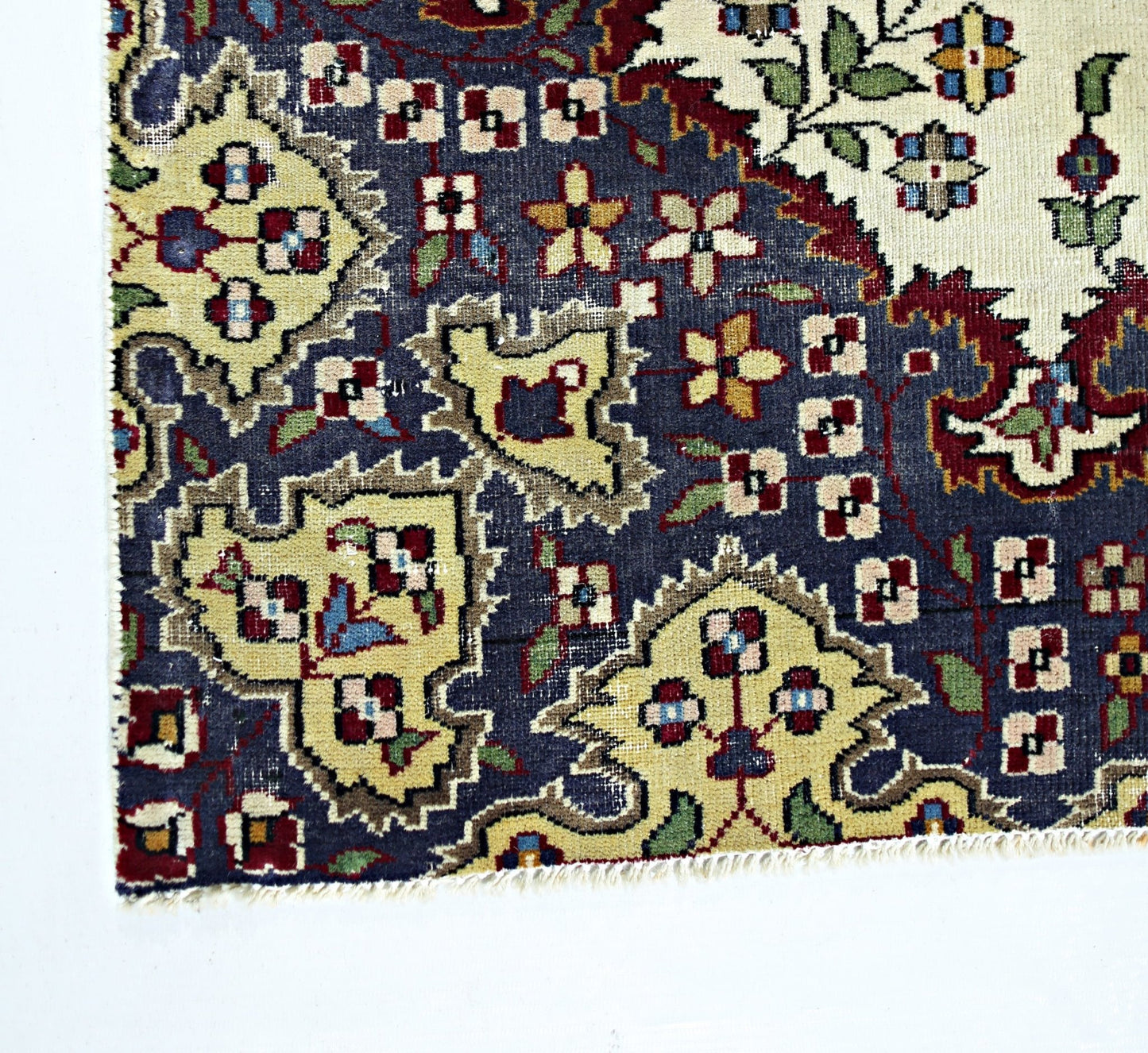 A corner view of a vintage Persian Kerman rug featuring intricate floral patterns in blue and cream.