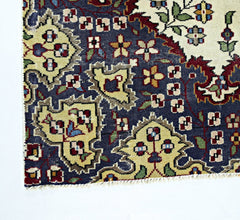 A corner view of a vintage Persian Kerman rug featuring intricate floral patterns in blue and cream.