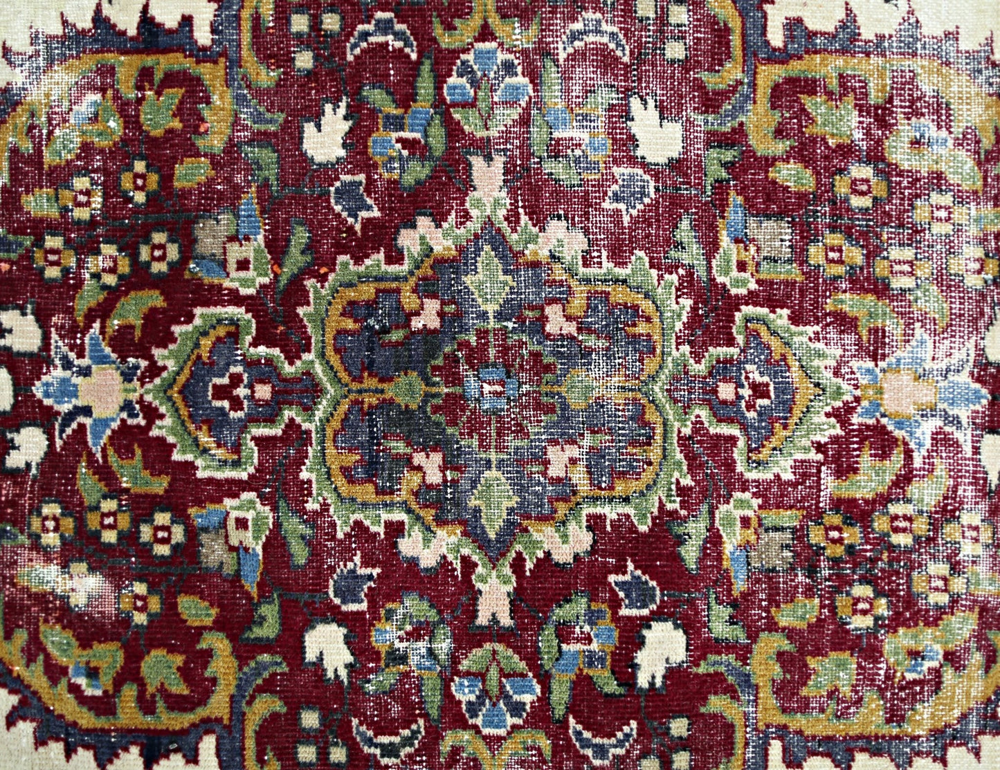 A vintage Persian Kerman rug featuring an intricate floral medallion design in deep red and blue.