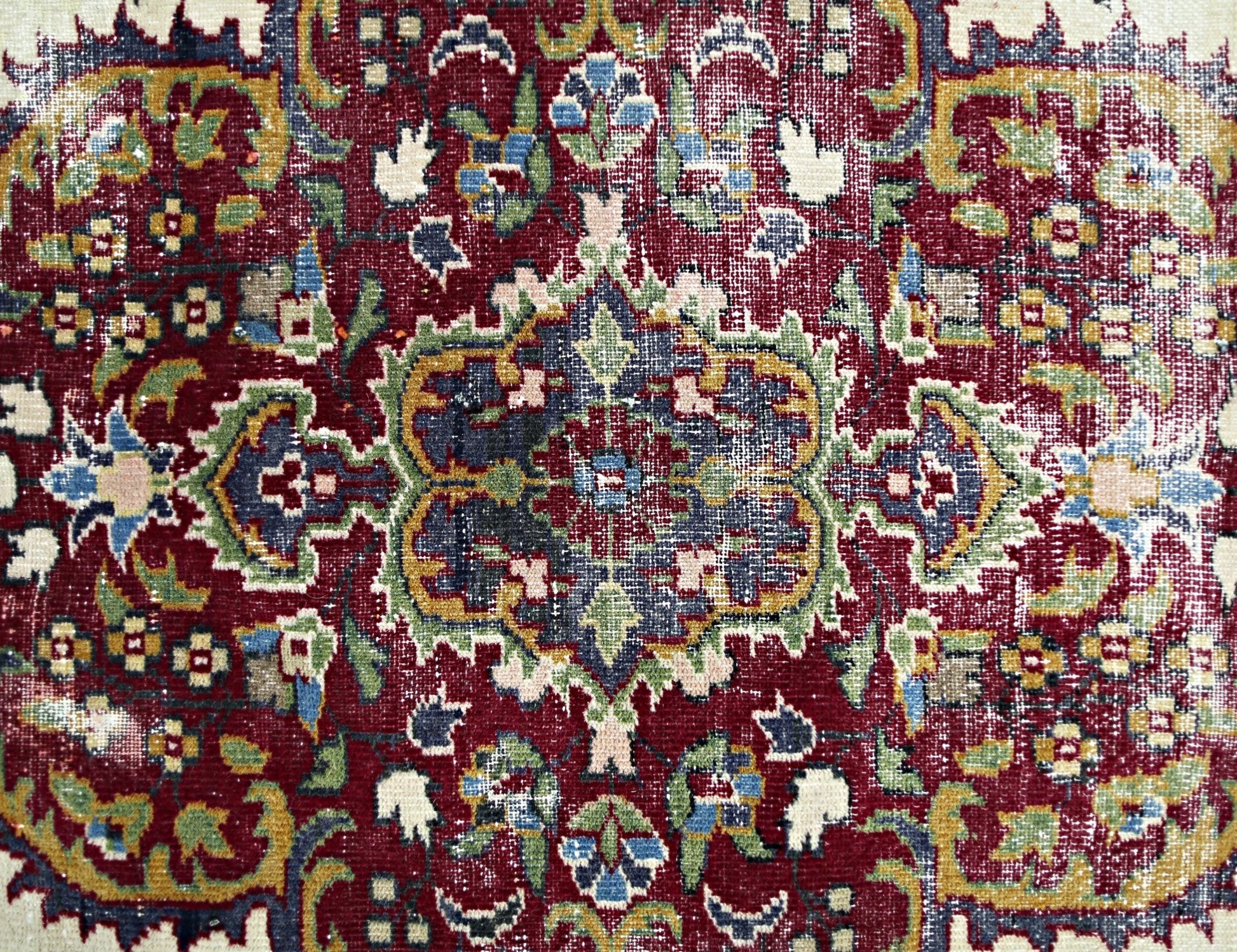 A vintage Persian Kerman rug featuring an intricate floral medallion design in deep red and blue.