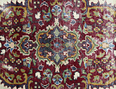 A vintage Persian Kerman rug featuring an intricate floral medallion design in deep red and blue.