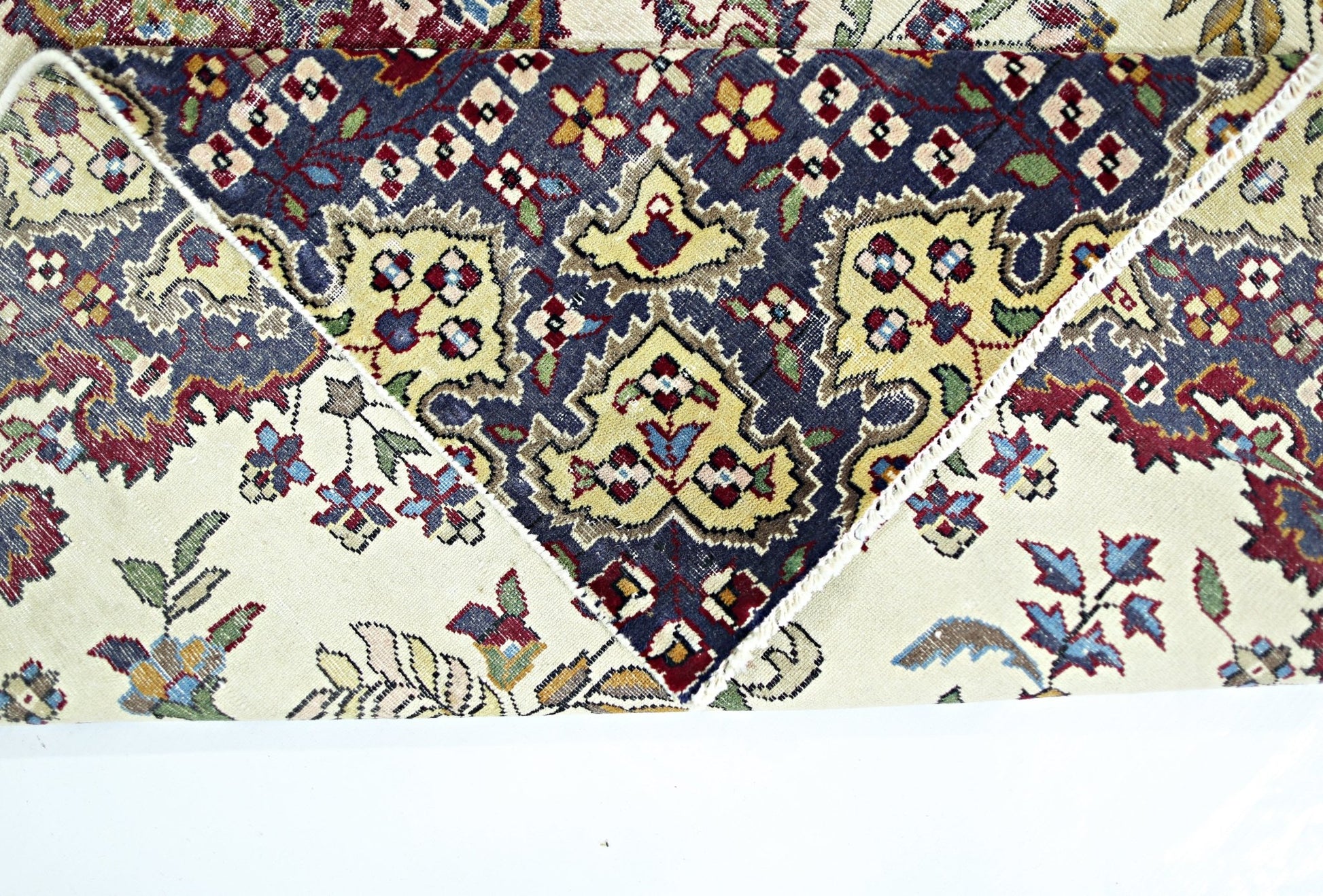 A vintage Persian Kerman rug featuring a dark blue central medallion with intricate floral motifs.