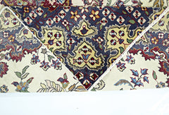 A vintage Persian Kerman rug featuring a dark blue central medallion with intricate floral motifs.
