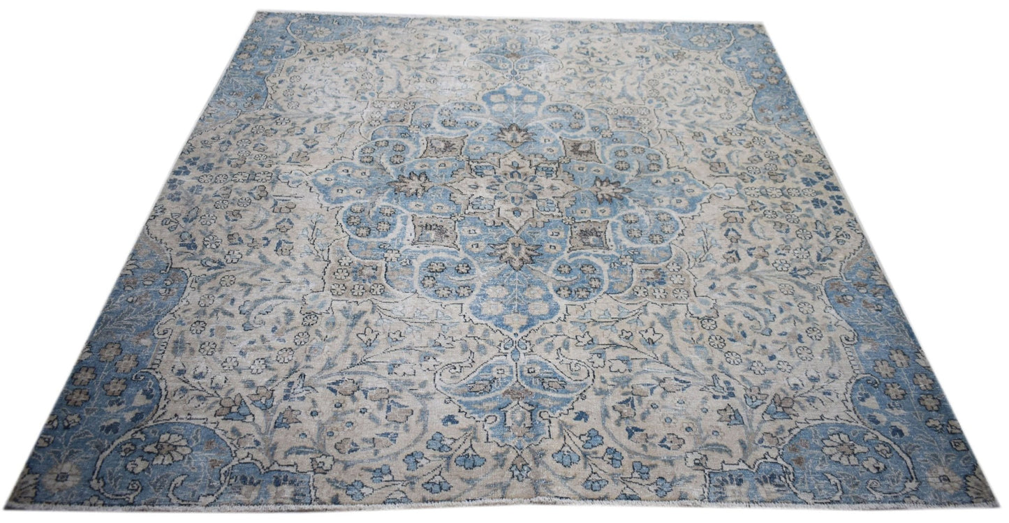 A vintage Persian Kerman rug featuring a central medallion and intricate floral patterns in blue.