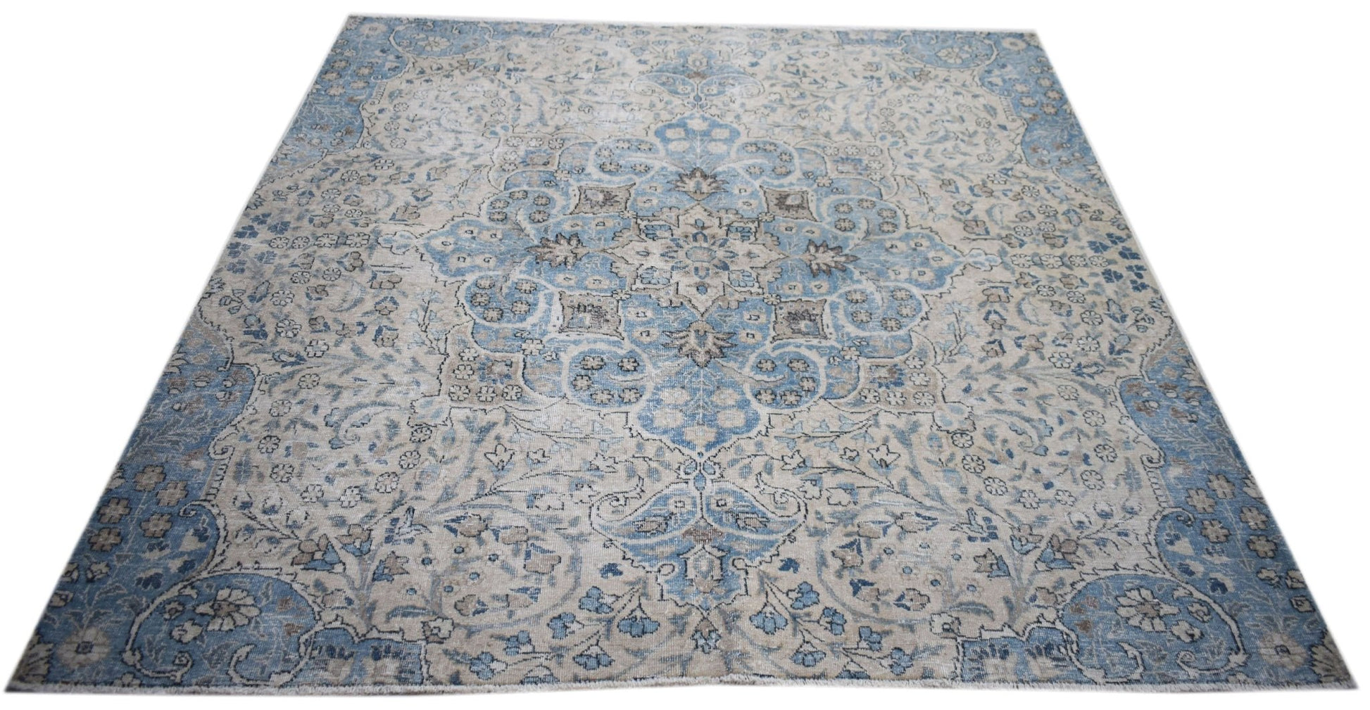 A vintage Persian Kerman rug featuring a central medallion and intricate floral patterns in blue.
