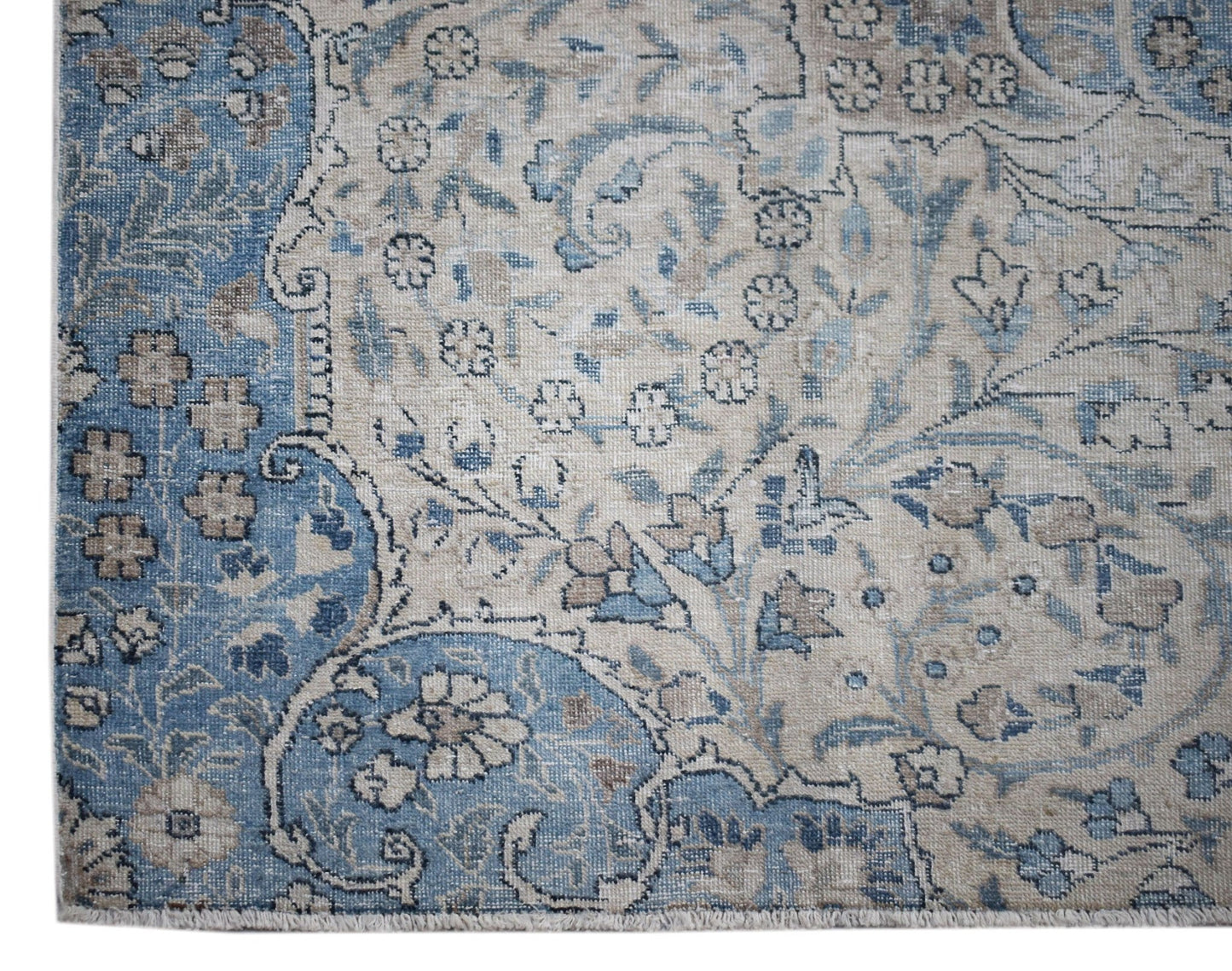 A vintage Persian Kerman rug featuring intricate floral patterns in shades of blue and beige.