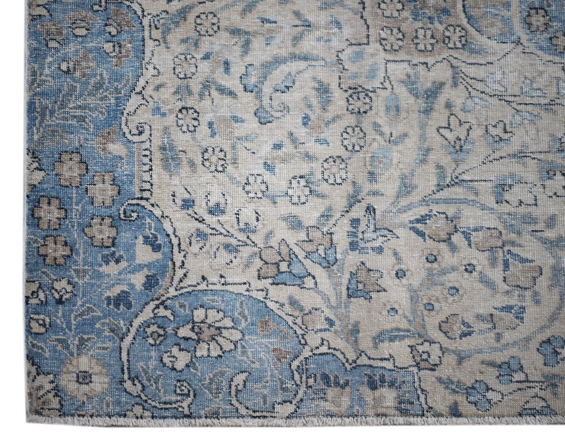 A vintage Persian Kerman rug featuring intricate floral patterns in shades of blue and beige.