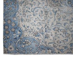 A vintage Persian Kerman rug featuring intricate floral patterns in shades of blue and beige.