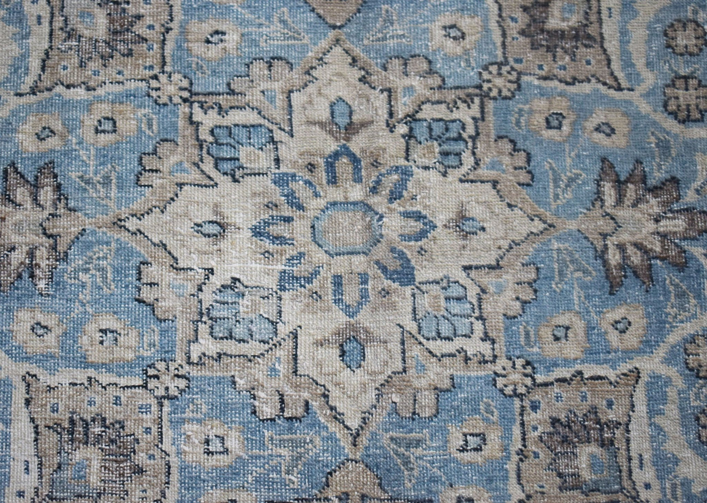 A vintage Persian Kerman rug featuring an intricate central medallion and floral motifs in blue.