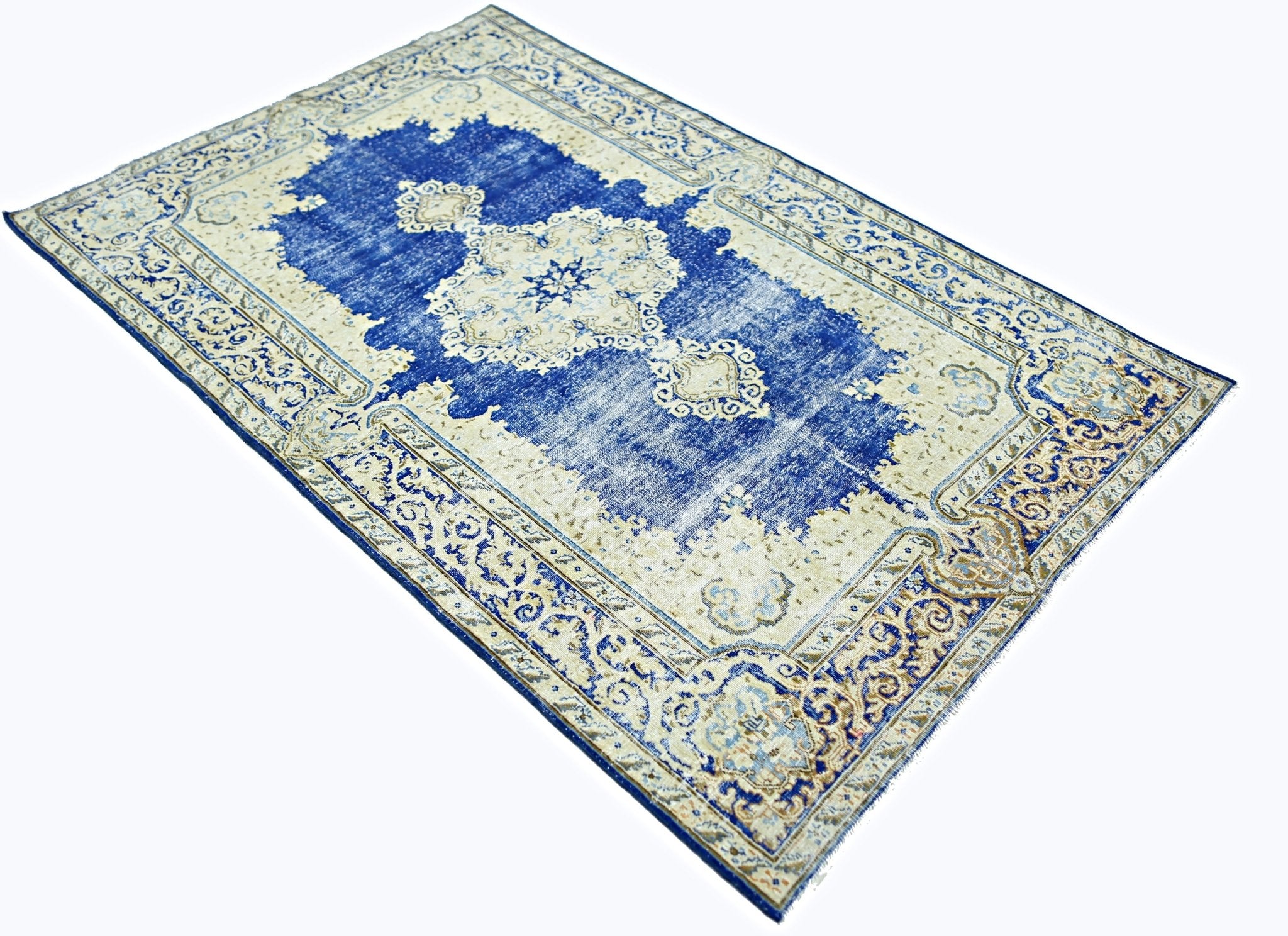 A vintage Persian Kerman rug featuring a central medallion and intricate floral patterns in blue.