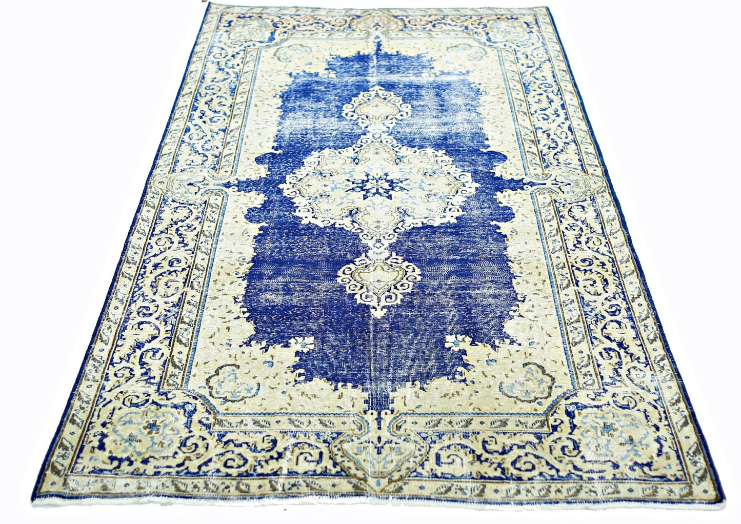 A vintage Persian Kerman rug featuring a central medallion and intricate floral patterns in blue.