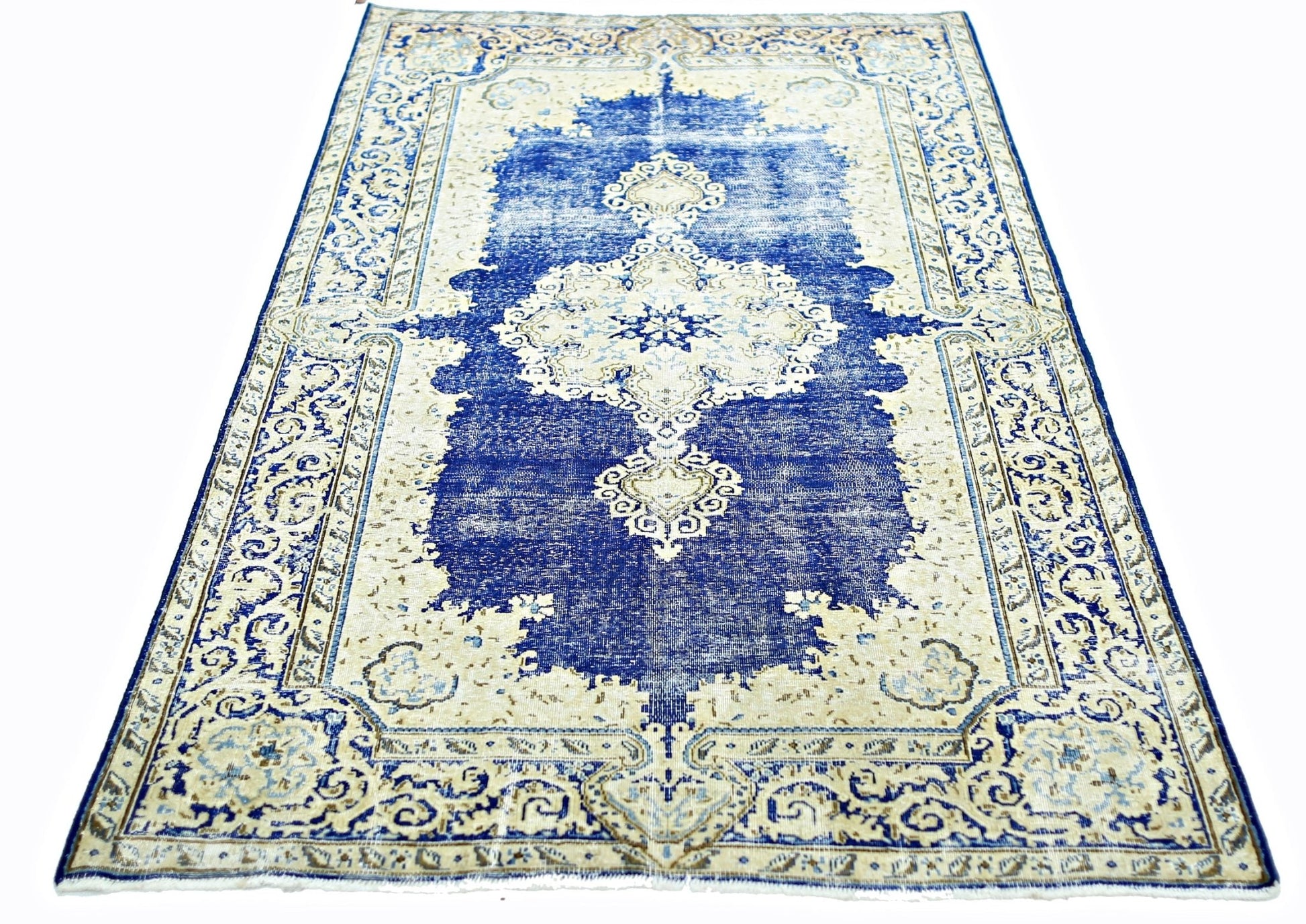 A vintage Persian Kerman rug featuring a central medallion and intricate floral patterns in blue.