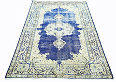 A vintage Persian Kerman rug featuring a central medallion and intricate floral patterns in blue.