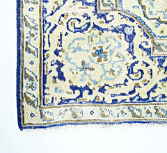 A vintage Persian Kerman rug featuring a blue and beige floral medallion pattern.