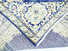 A folded vintage Persian Kerman rug featuring an intricate blue and cream floral medallion design.