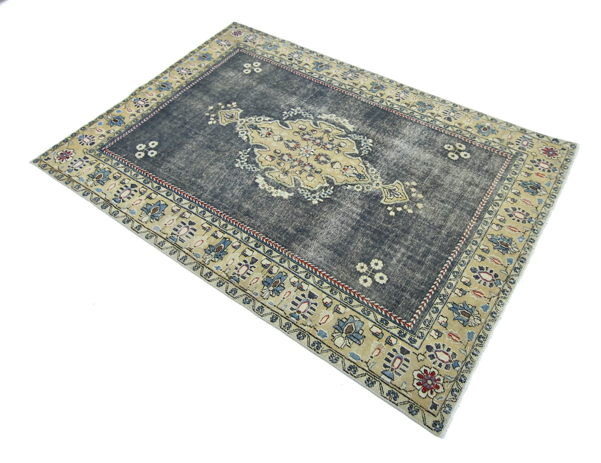 A vintage Persian Kerman rug featuring a central medallion on a distressed dark blue field.