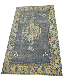 A vintage Persian Kerman rug featuring a central medallion on a distressed blue field.