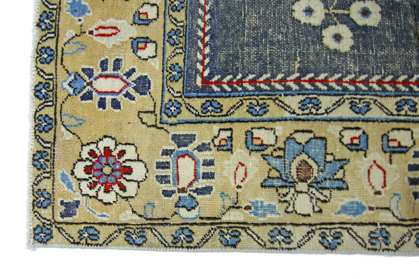 A vintage Persian Kerman rug featuring intricate floral patterns in blue, red, and cream tones.
