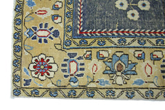 A vintage Persian Kerman rug featuring intricate floral patterns in blue, red, and cream tones.