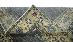 A vintage Persian Kerman rug with a folded corner revealing a blue and beige floral pattern.