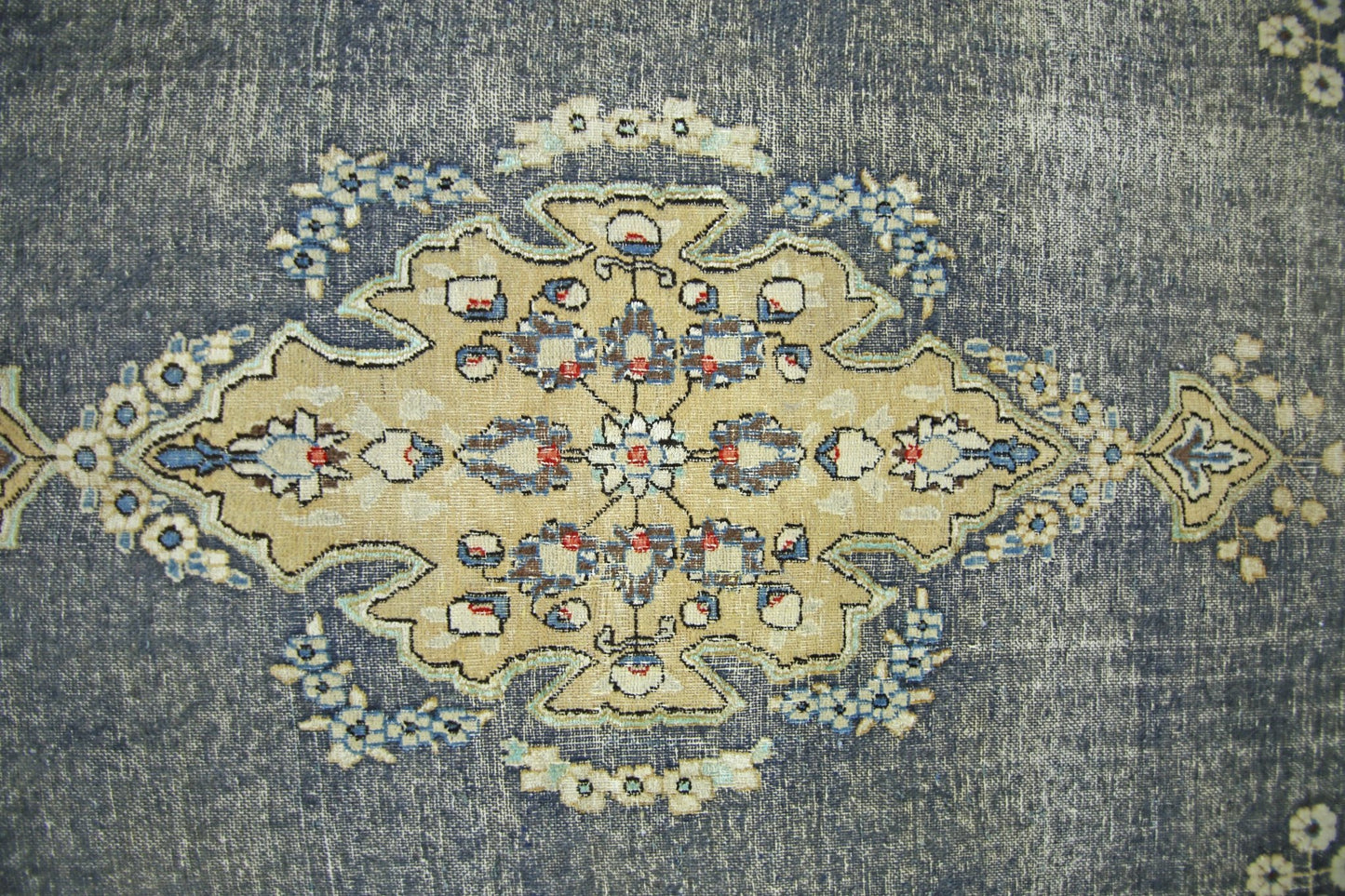 A vintage Persian Kerman rug featuring a central floral medallion on a distressed blue background.