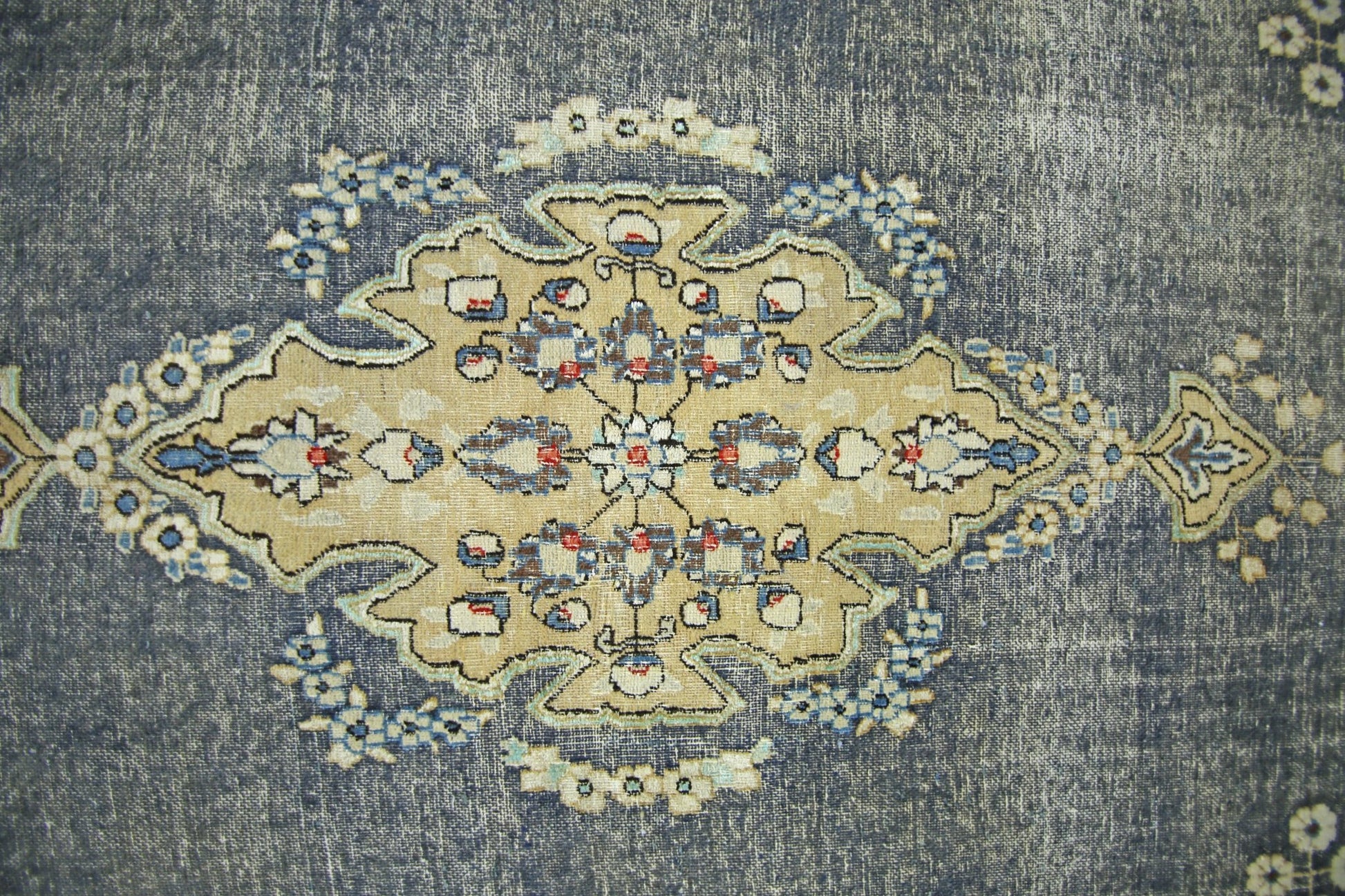 A vintage Persian Kerman rug featuring a central floral medallion on a distressed blue background.