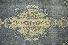 A vintage Persian Kerman rug featuring a central floral medallion on a distressed blue background.