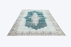 A vintage Persian Kerman rug featuring a central medallion on a teal field with floral borders.