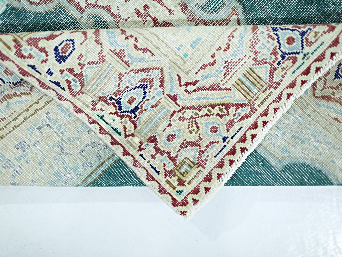 A vintage Persian Kerman rug featuring an intricate floral medallion pattern in teal and cream.