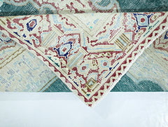 A vintage Persian Kerman rug featuring an intricate floral medallion pattern in teal and cream.