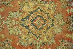A vintage Persian Kerman rug featuring an intricate floral medallion on a warm orange background.