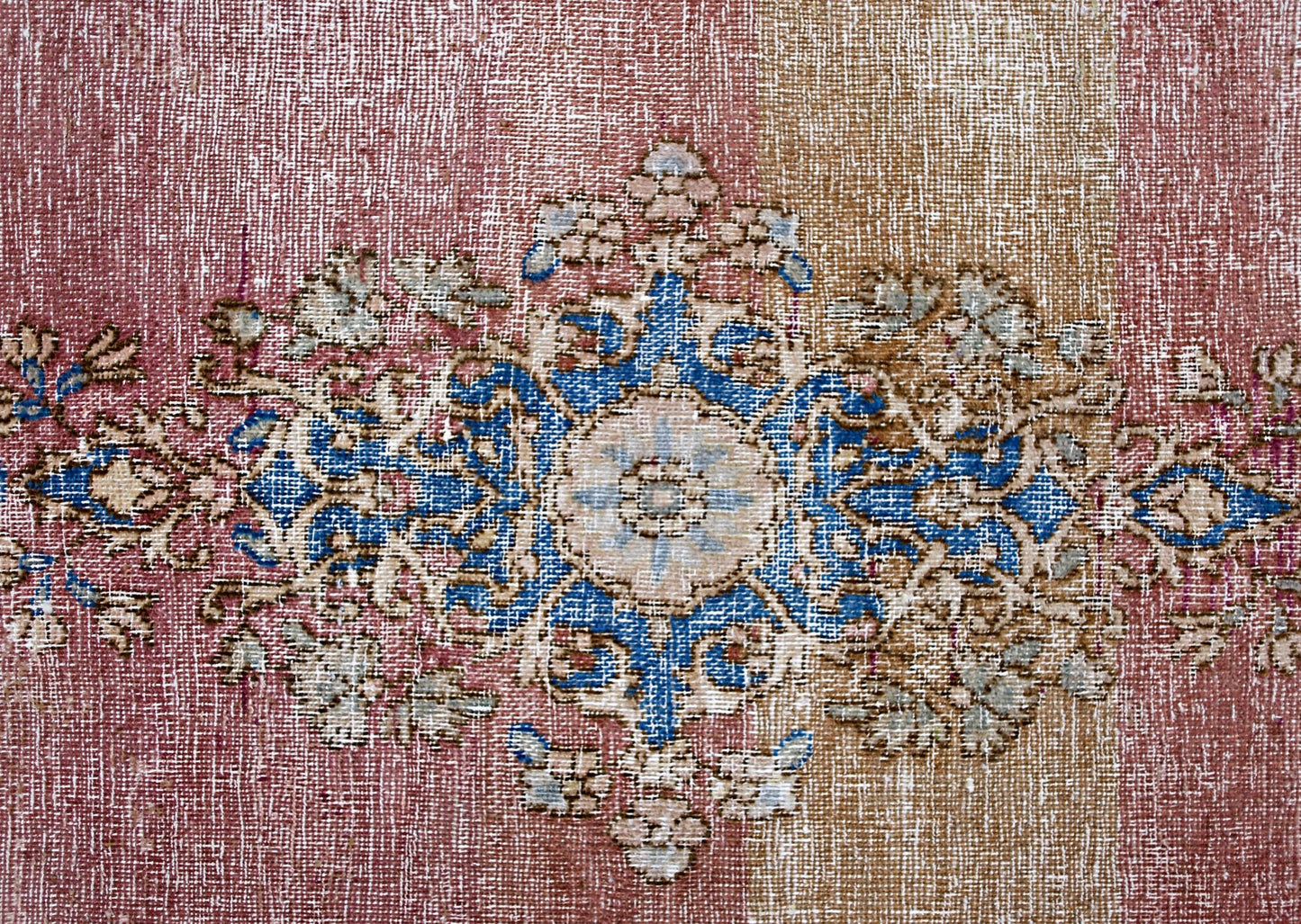 A vintage Persian Kerman rug featuring a central blue and cream floral medallion on a faded red and tan background.